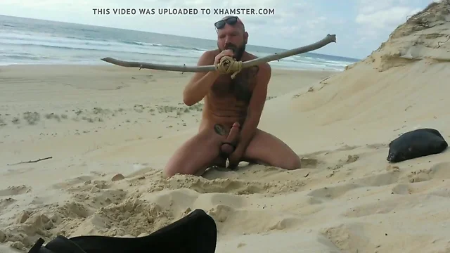 guy fucks  himself on the beach with a  wooden dildo