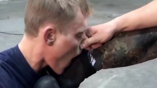 A lucky guy is allowed to lick the boots of two german soldiers